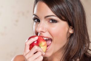 Smiling young woman eating apple