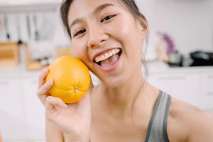 Smiling young woman holding an orange